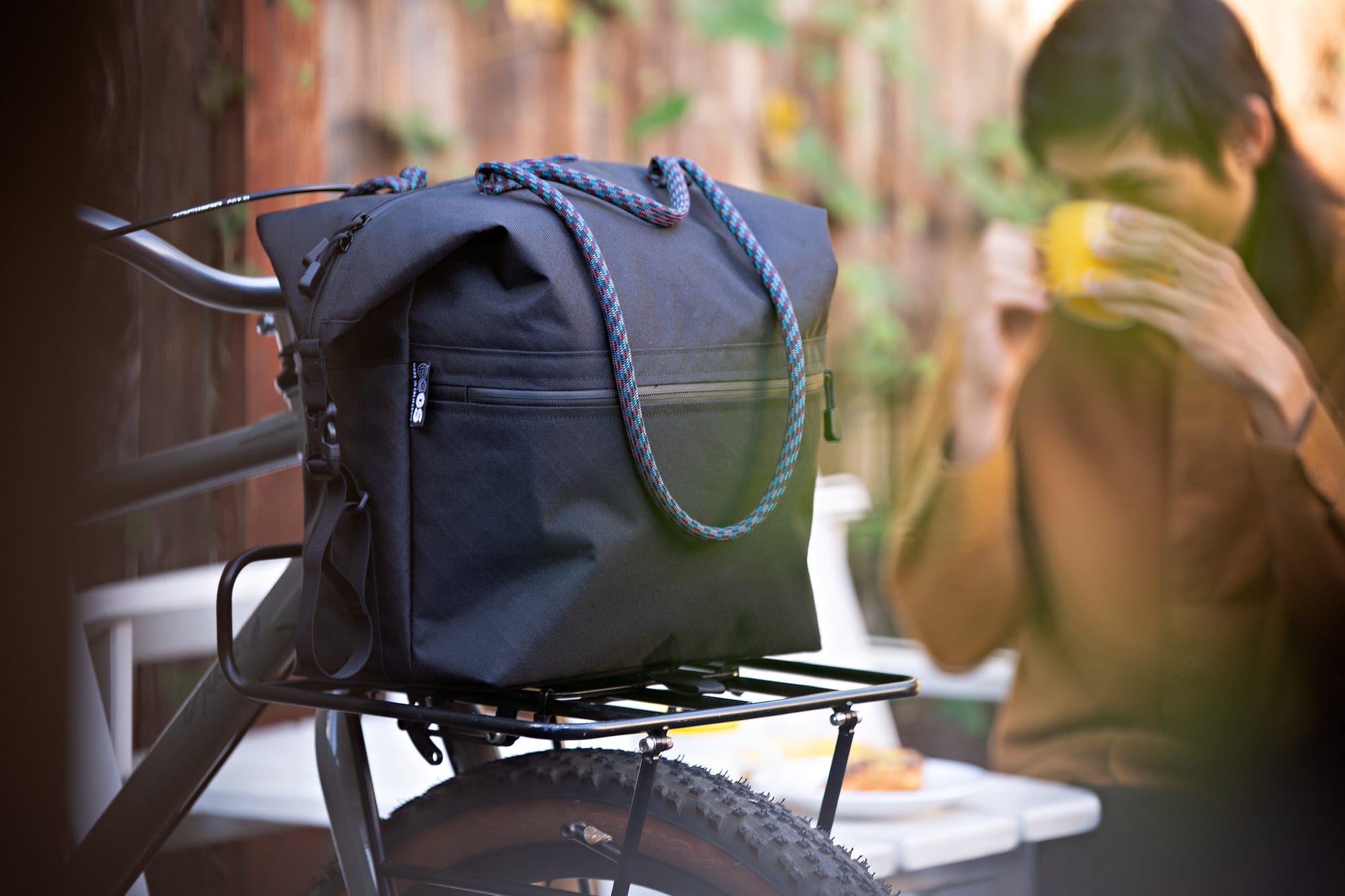 Outer Shell QR Tote with blue and purple handles mounted on a bicycle front rack.