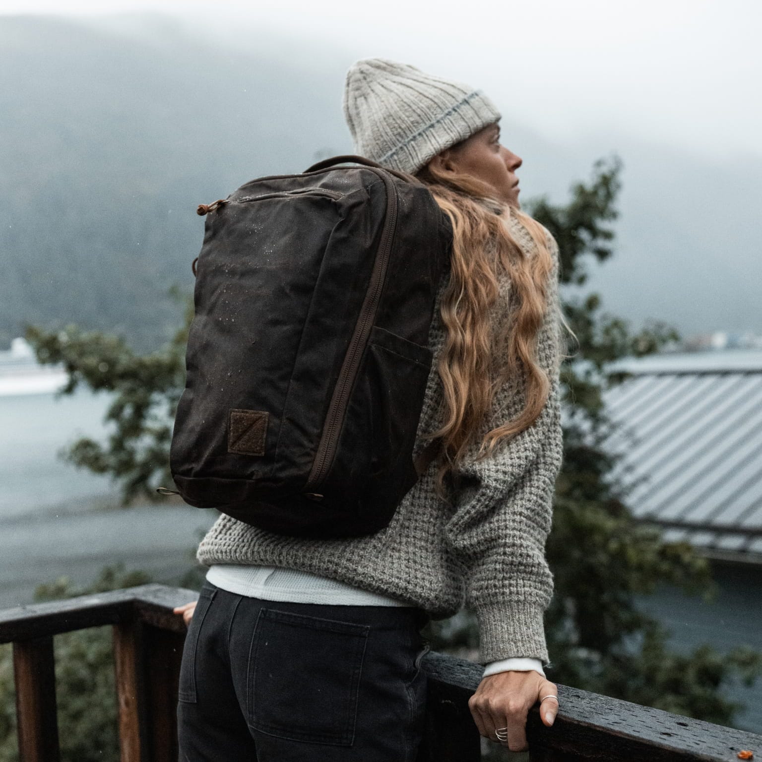 Waxed Tan CIVIC Travel Bag worn on the back beside an Alaskan waterside.