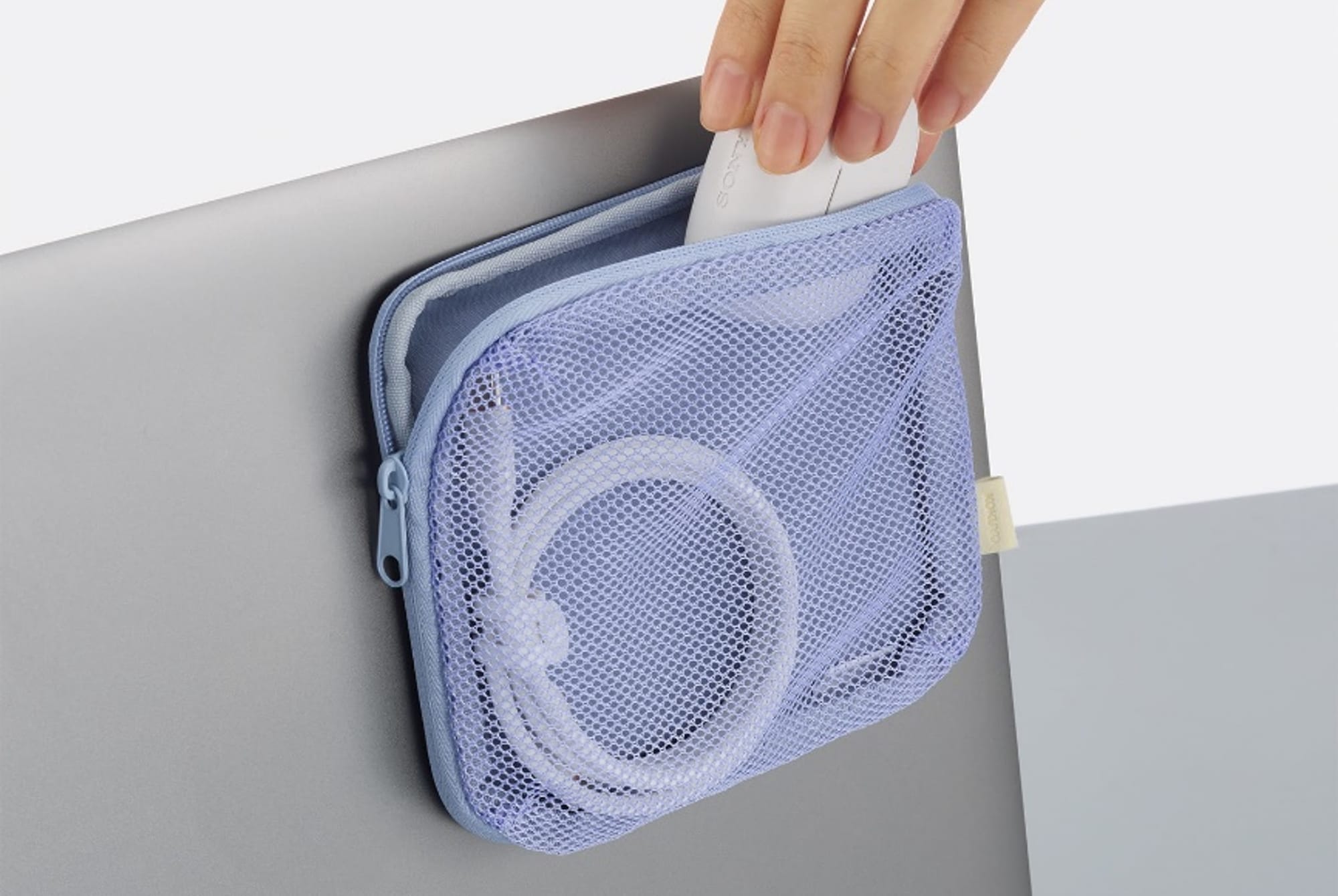 Lilac KOKUYO Stick-On Pouch attached to a laptop lid, with charging accessories inside.
