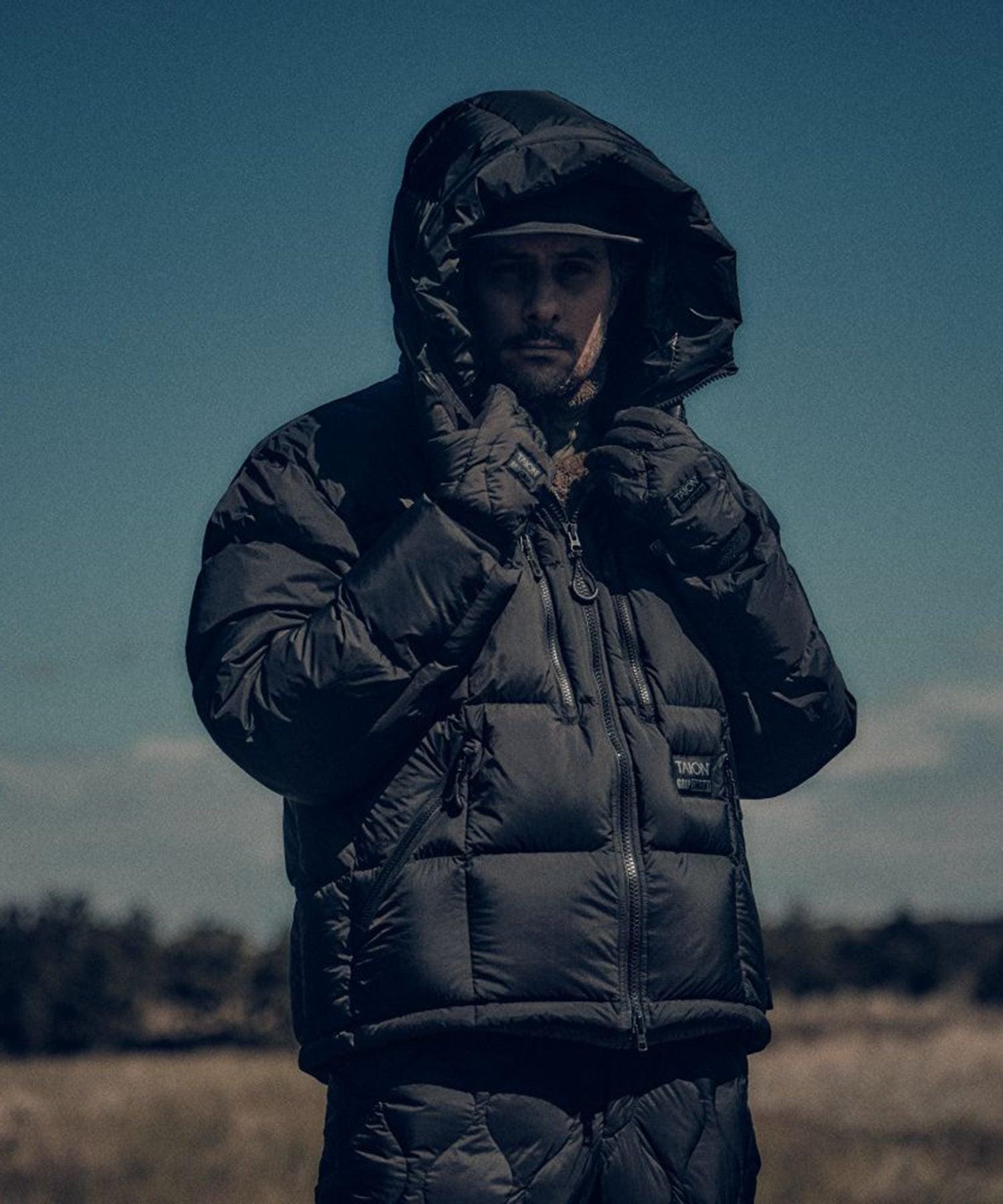 Front view of the jacket with hood up and arms raised against cold weather.