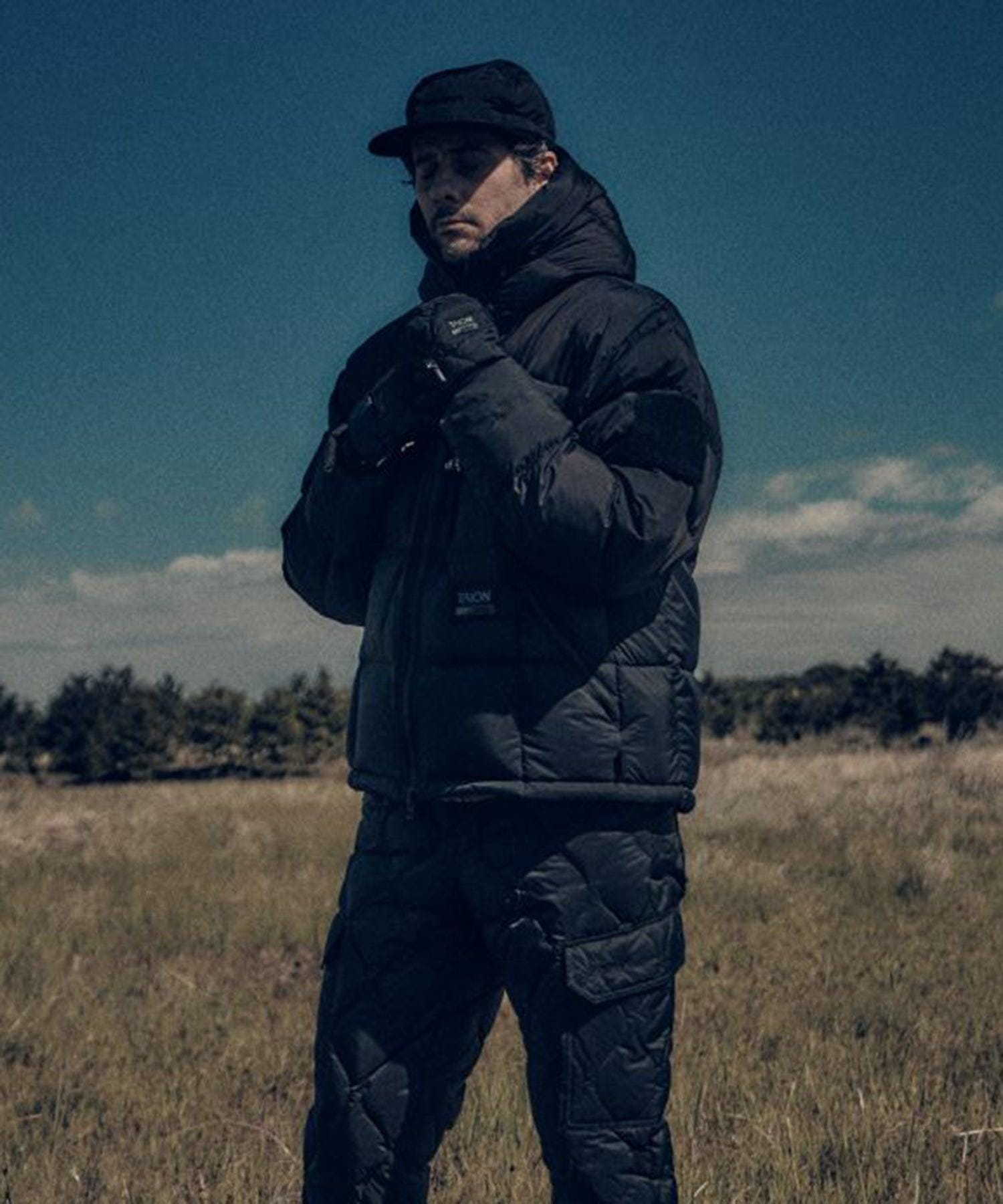 Jacket shown front-on while the wearer adjusts the front closure outdoors.