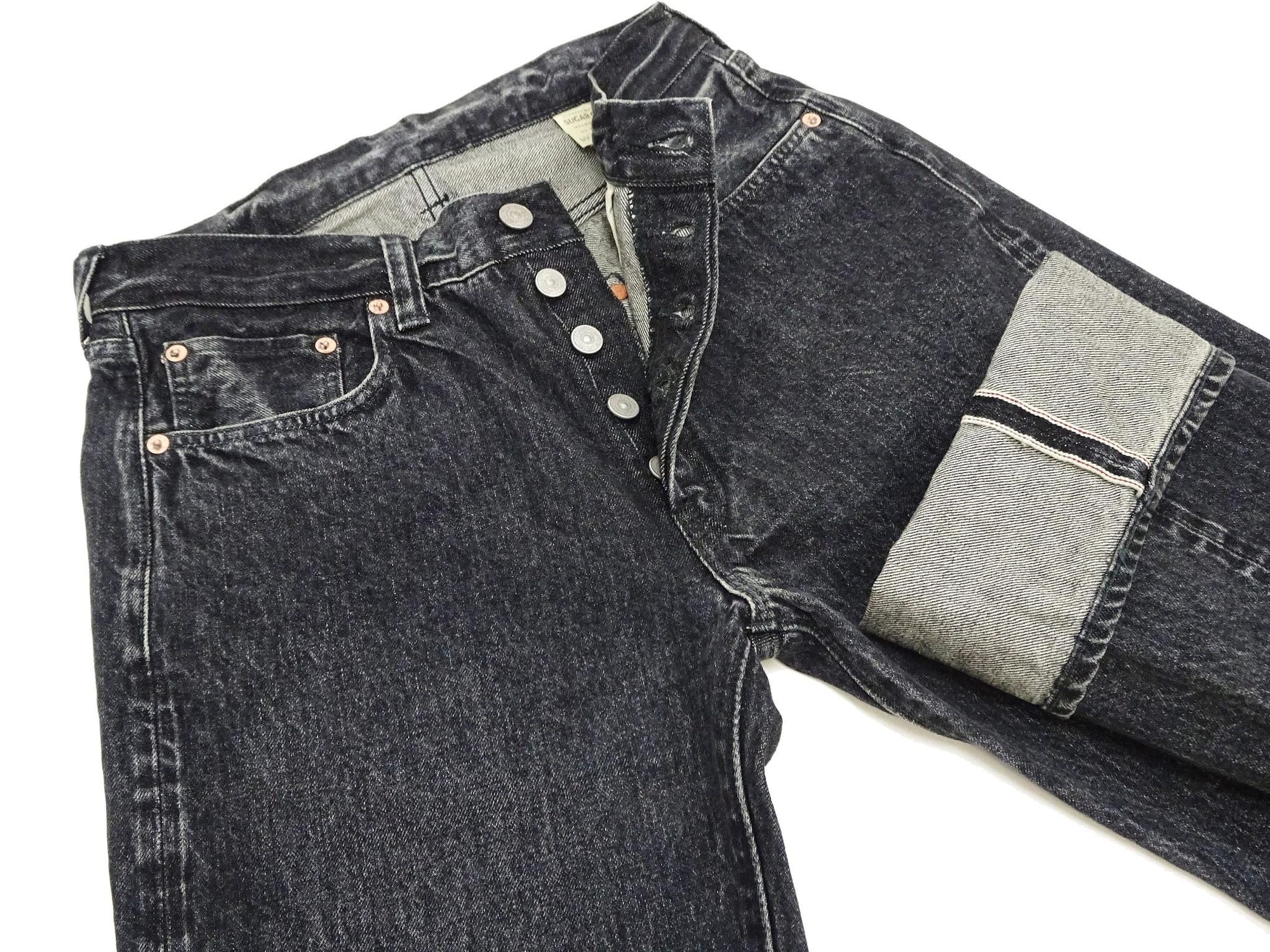 Waist and fly close view showing the faded black denim and selvedge cuff.