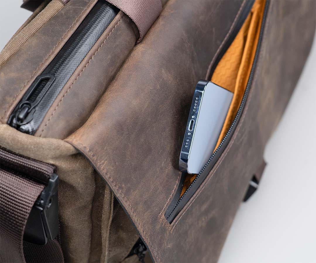 A small item being placed in the flap’s zipped pocket.