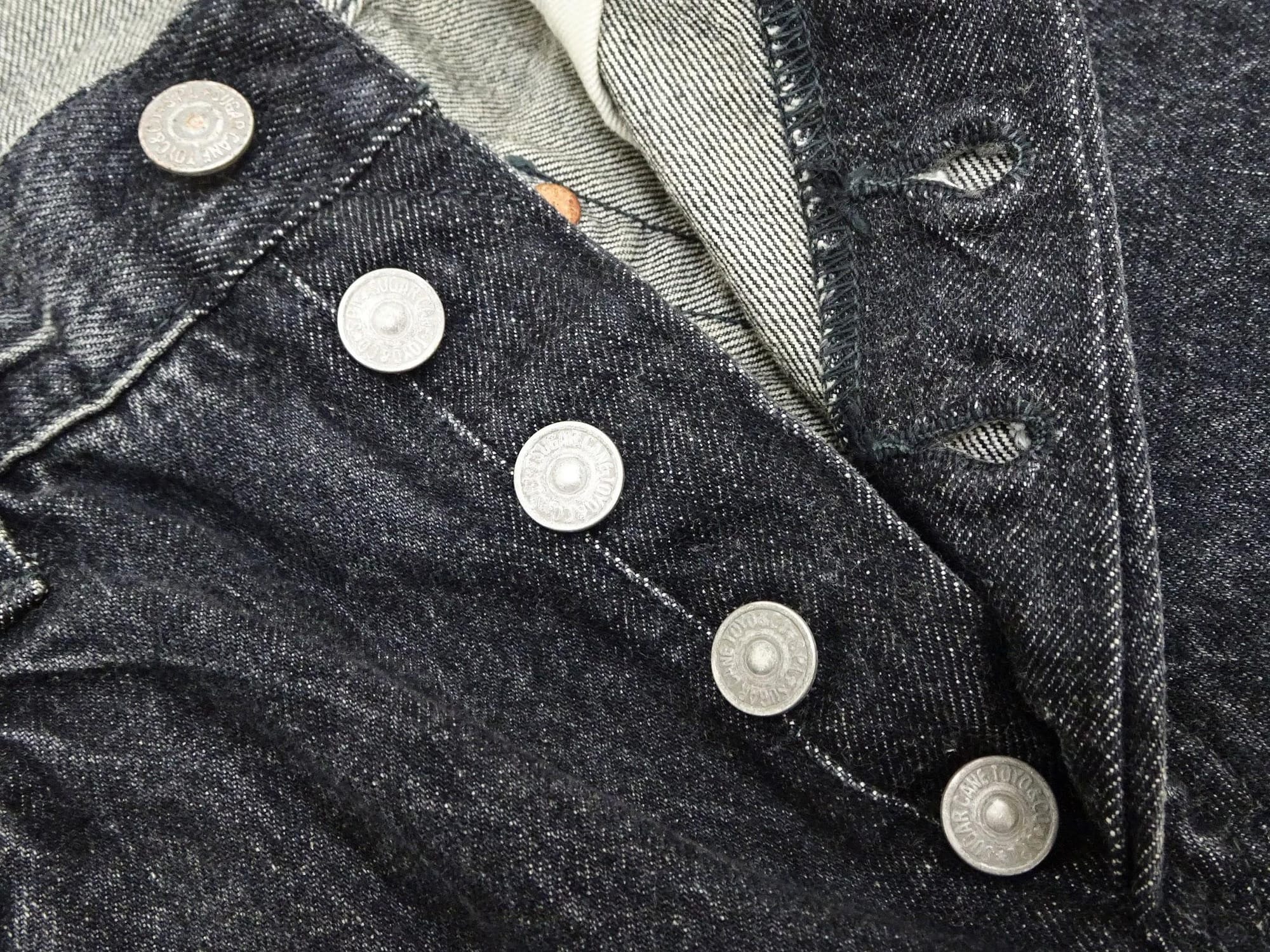 Close-up of the button fly and black denim weave.