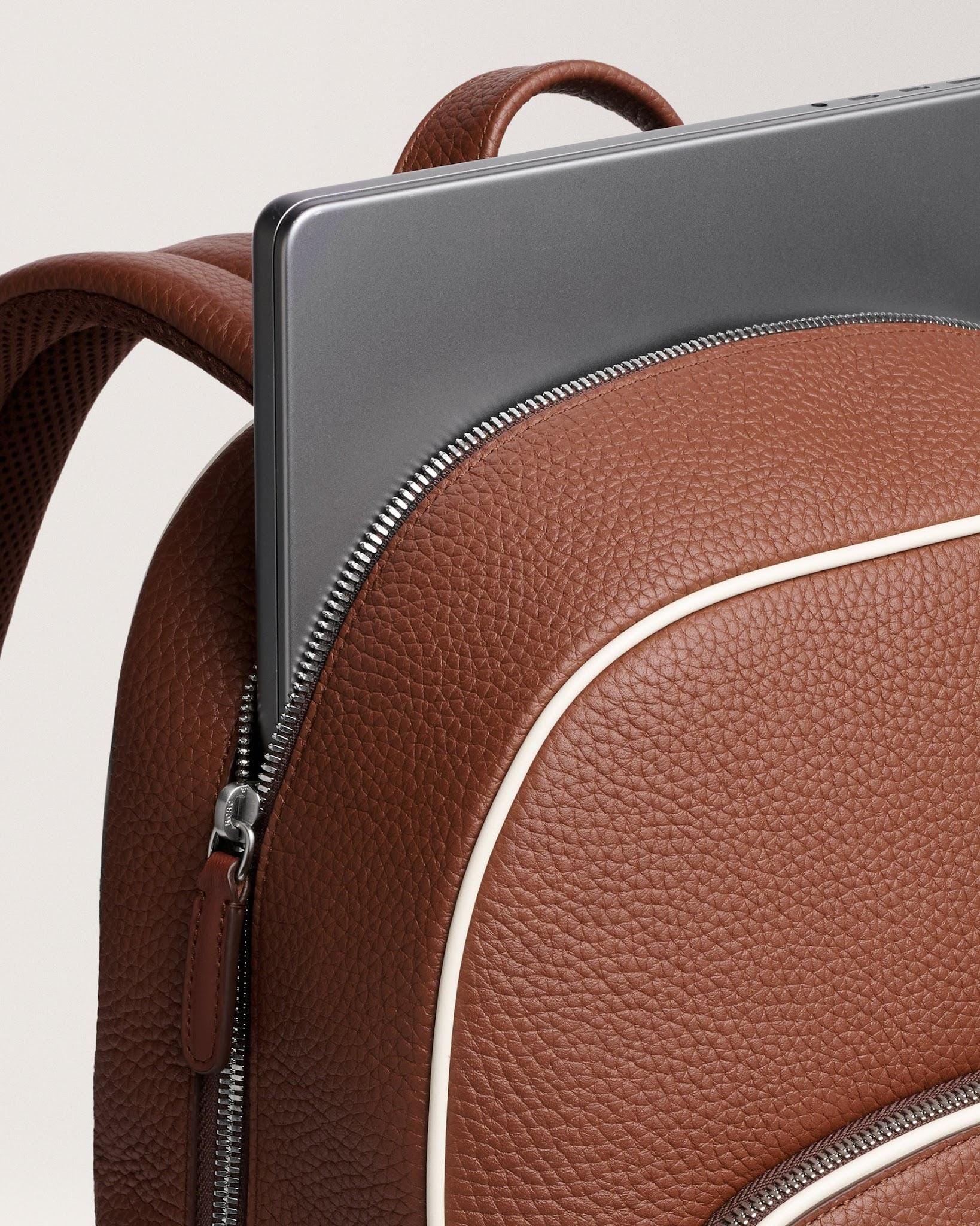 Laptop being placed through an opened compartment of the Grove backpack.