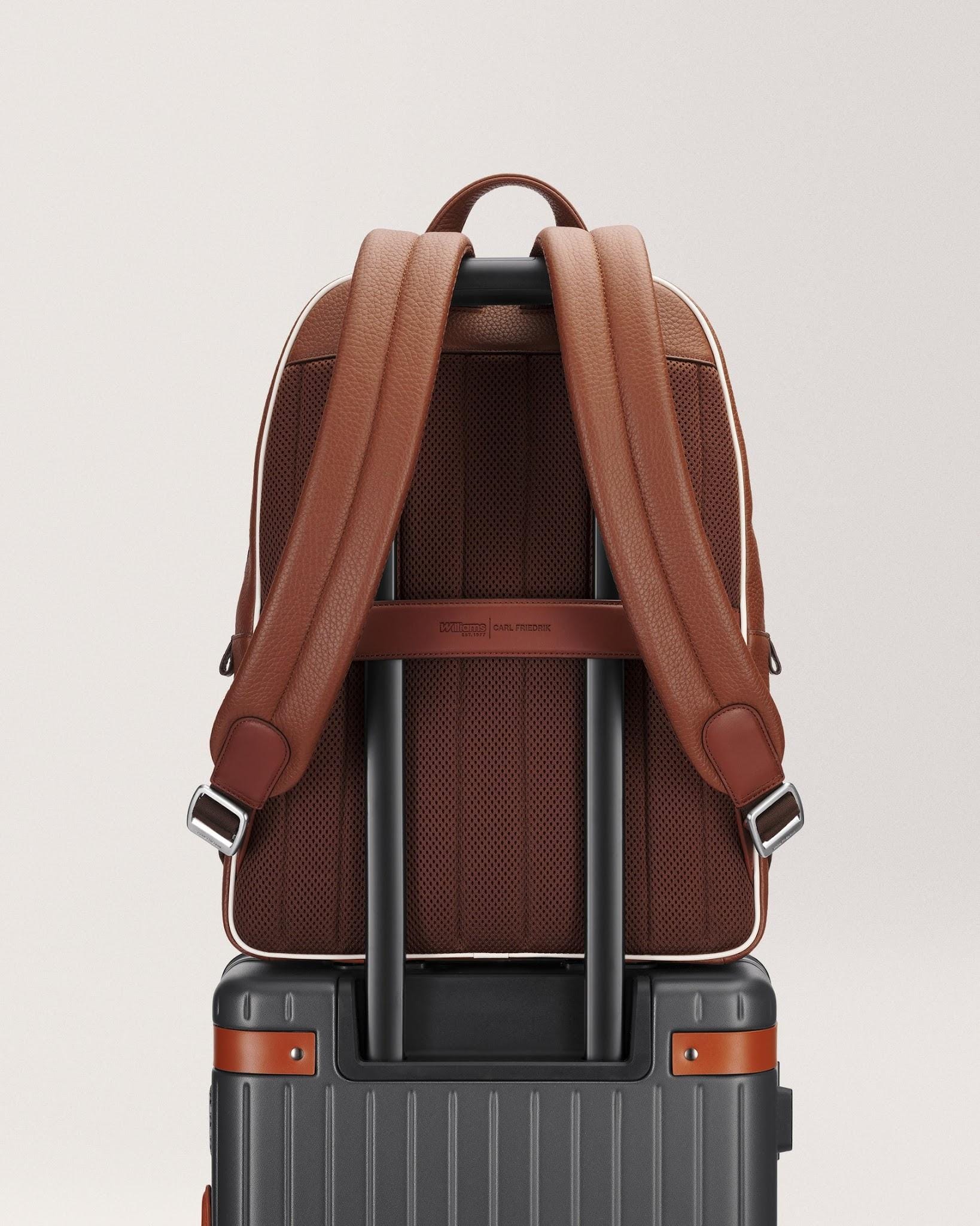 Rear of the Grove backpack with straps and luggage sleeve over suitcase handle.