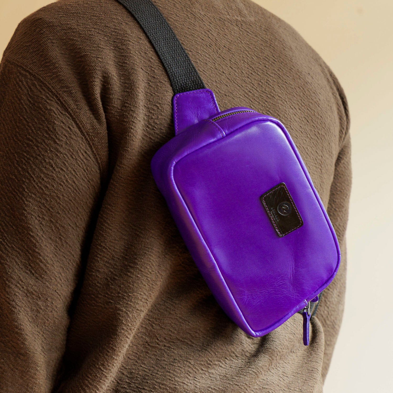 Purple leather sling bag worn across the body in the fall-release preview