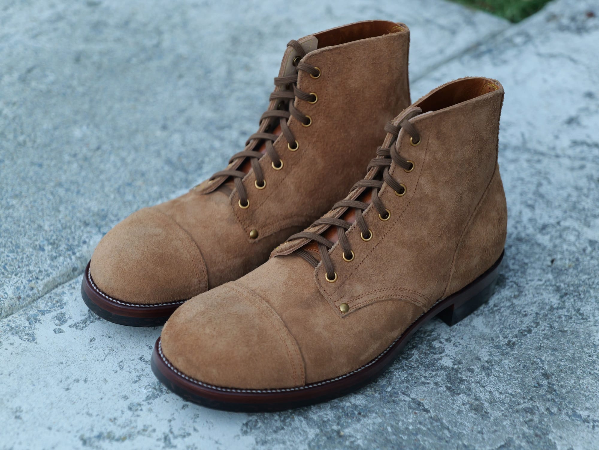 Infantry roughout boots photographed together on a grey surface.