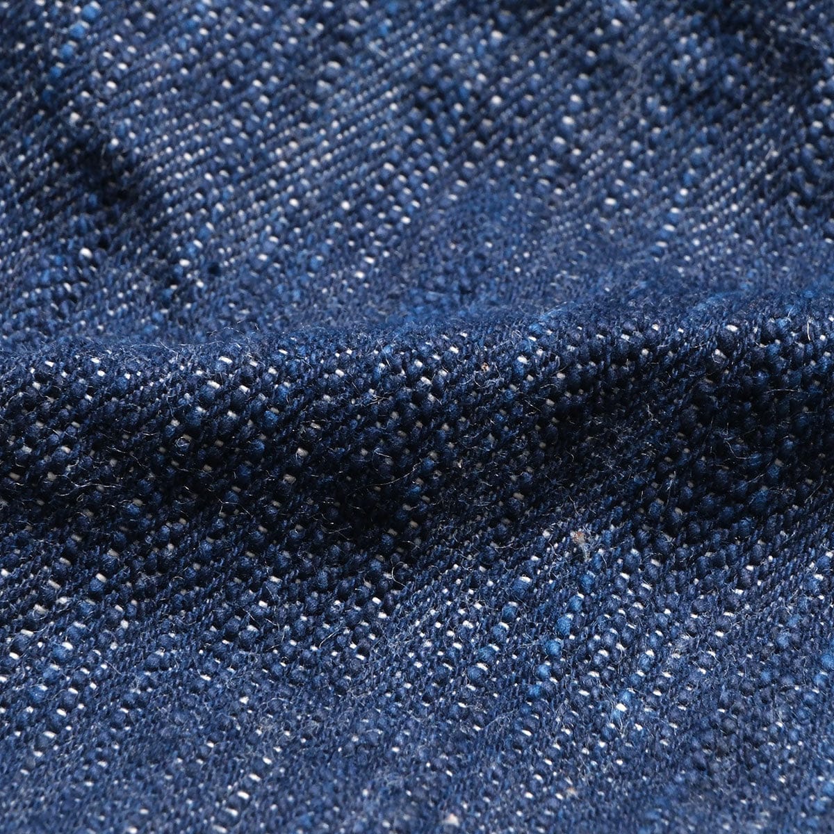 Close view of the irregular indigo and ecru denim texture.