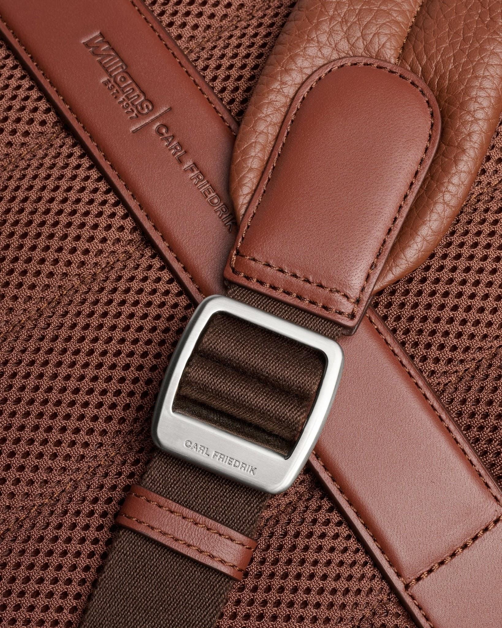 Rear harness stitching, leather tab and branded buckle close-up.