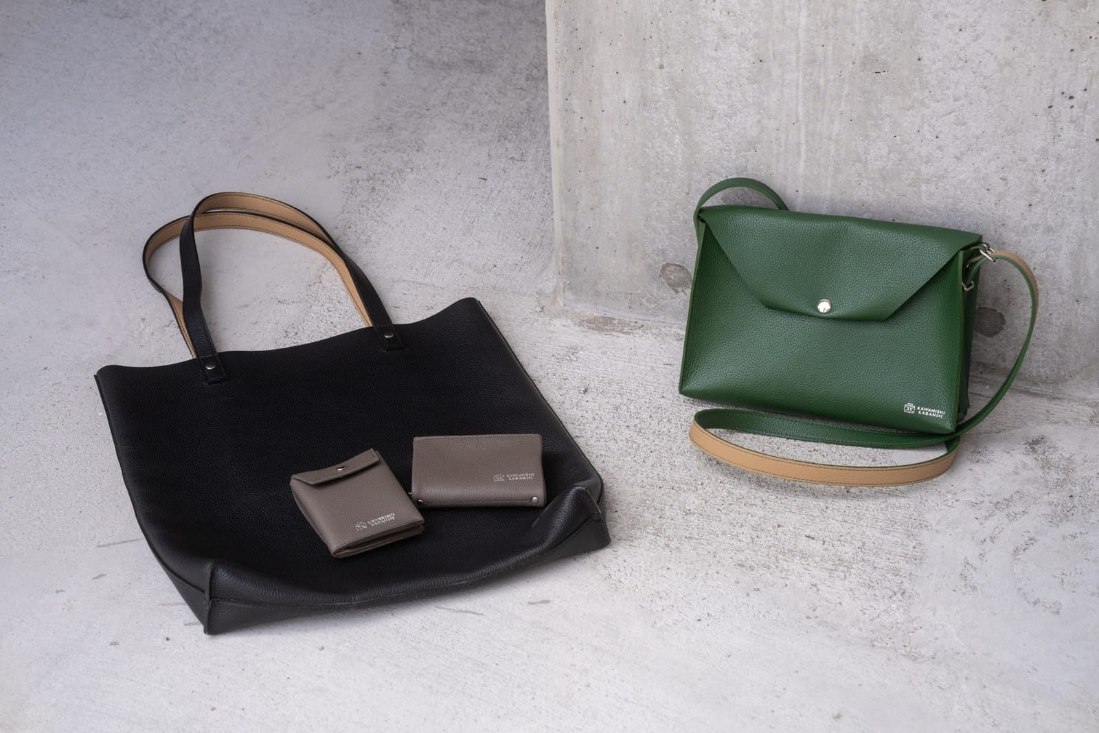 Kawanishi Dual leather tote, shoulder bag, wallet and key case on a concrete floor.