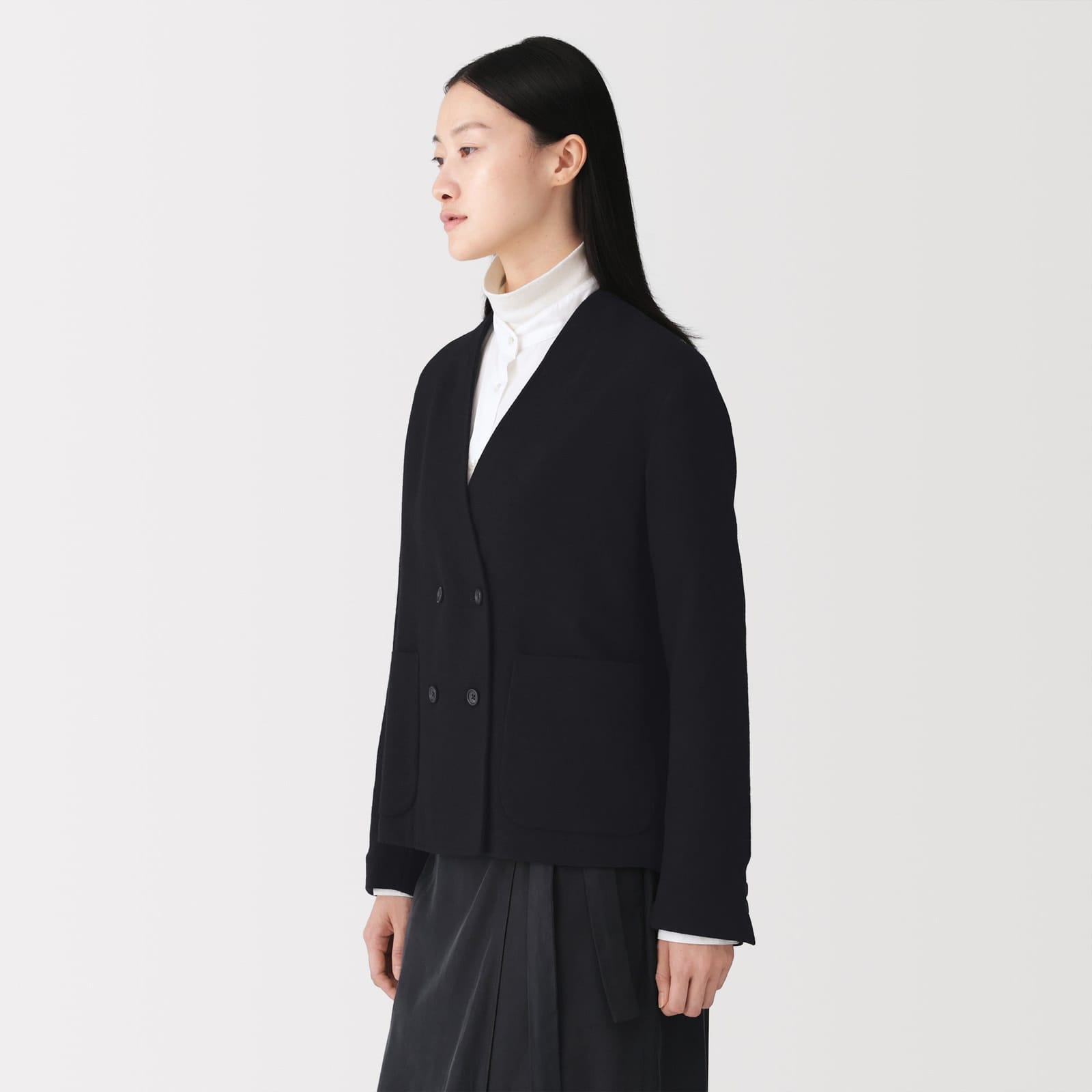 Black version of the MUJI Labo collarless jacket worn over a white high-neck top