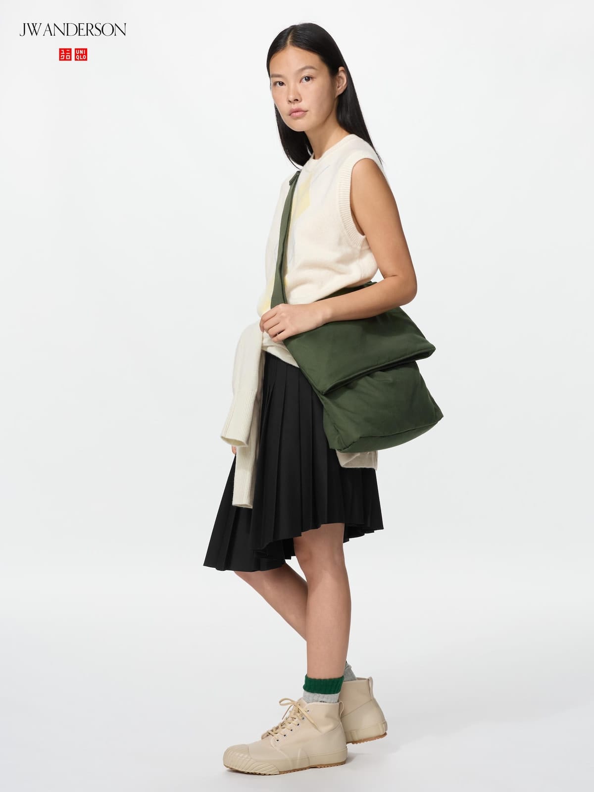Model wearing the olive shoulder bag with a light sleeveless top and dark skirt
