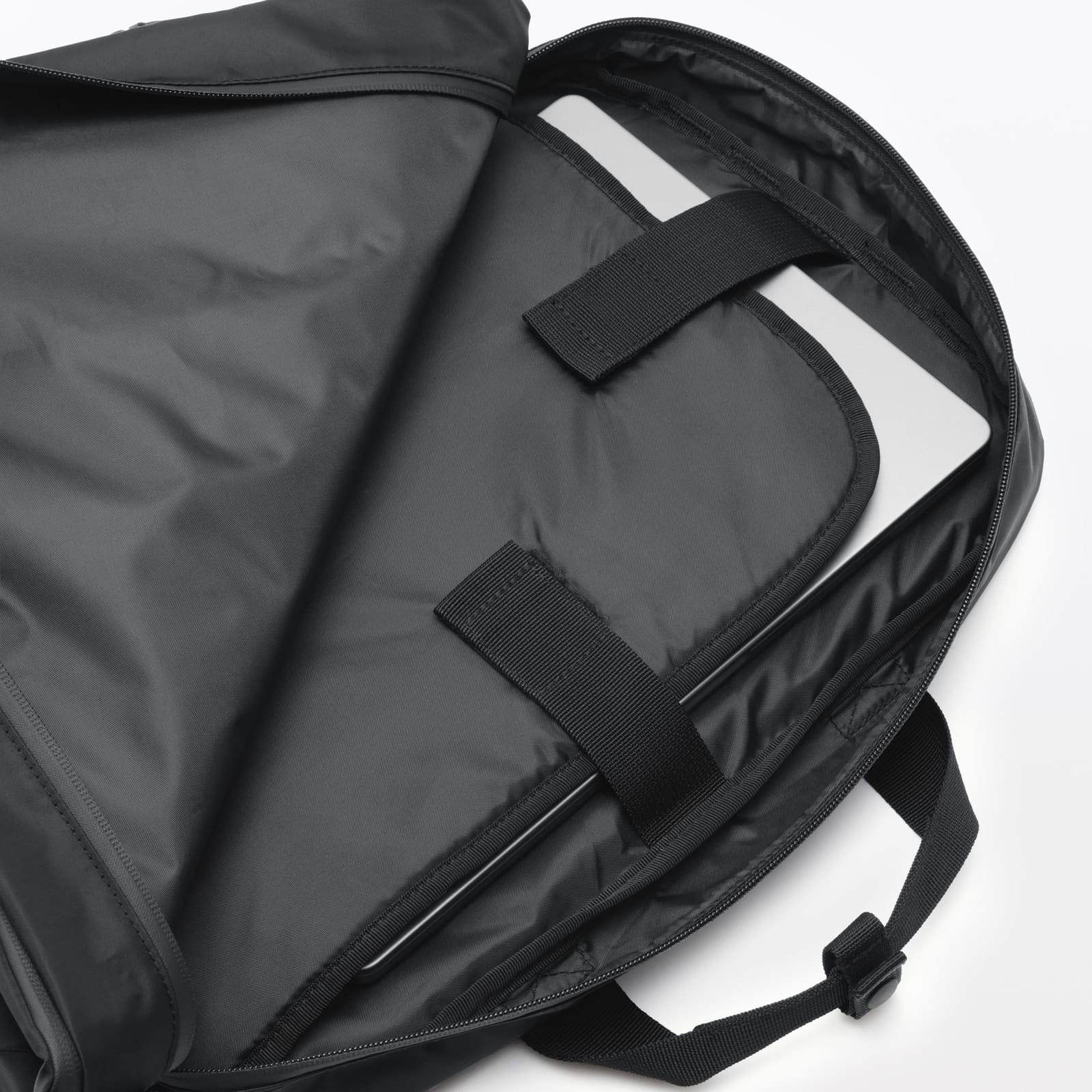 Laptop tucked inside the dedicated compartment of the black MUJI bag