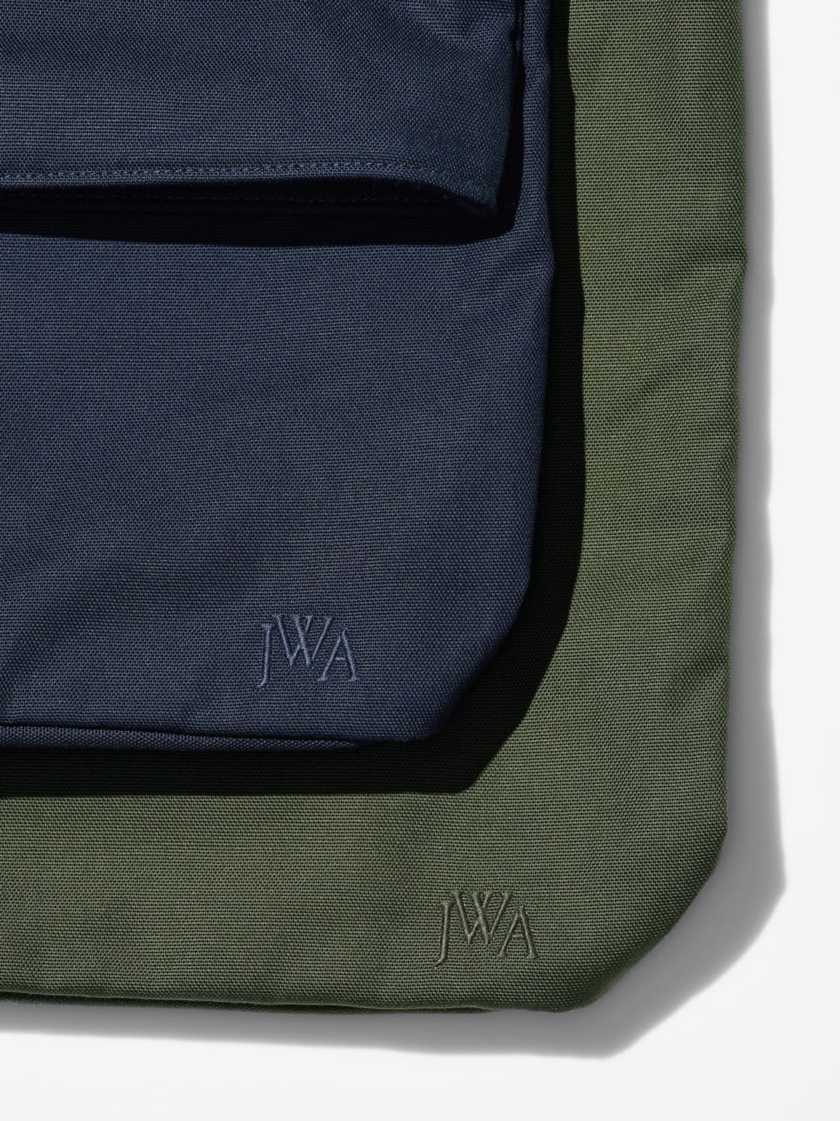 Close-up of tonal JWA embroidery on navy and olive canvas