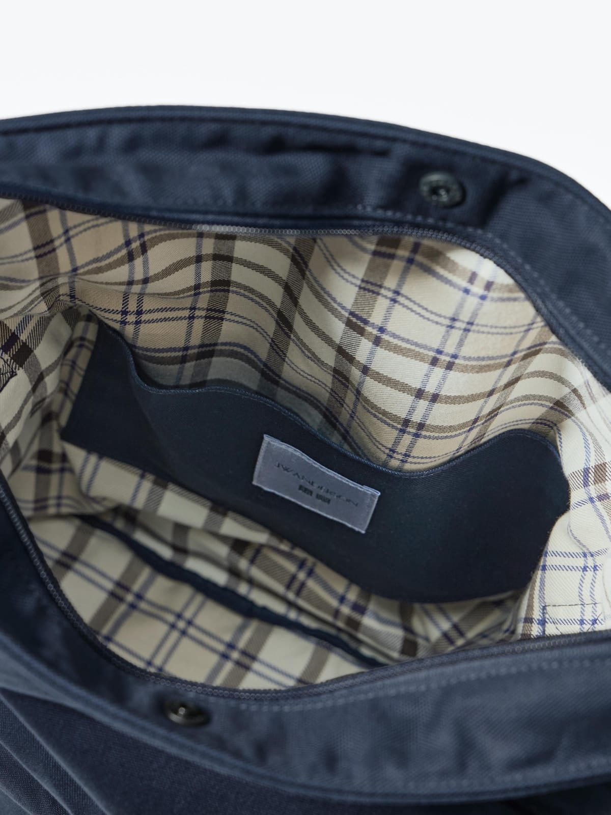 Checked interior of the navy shoulder bag with internal pocket and label