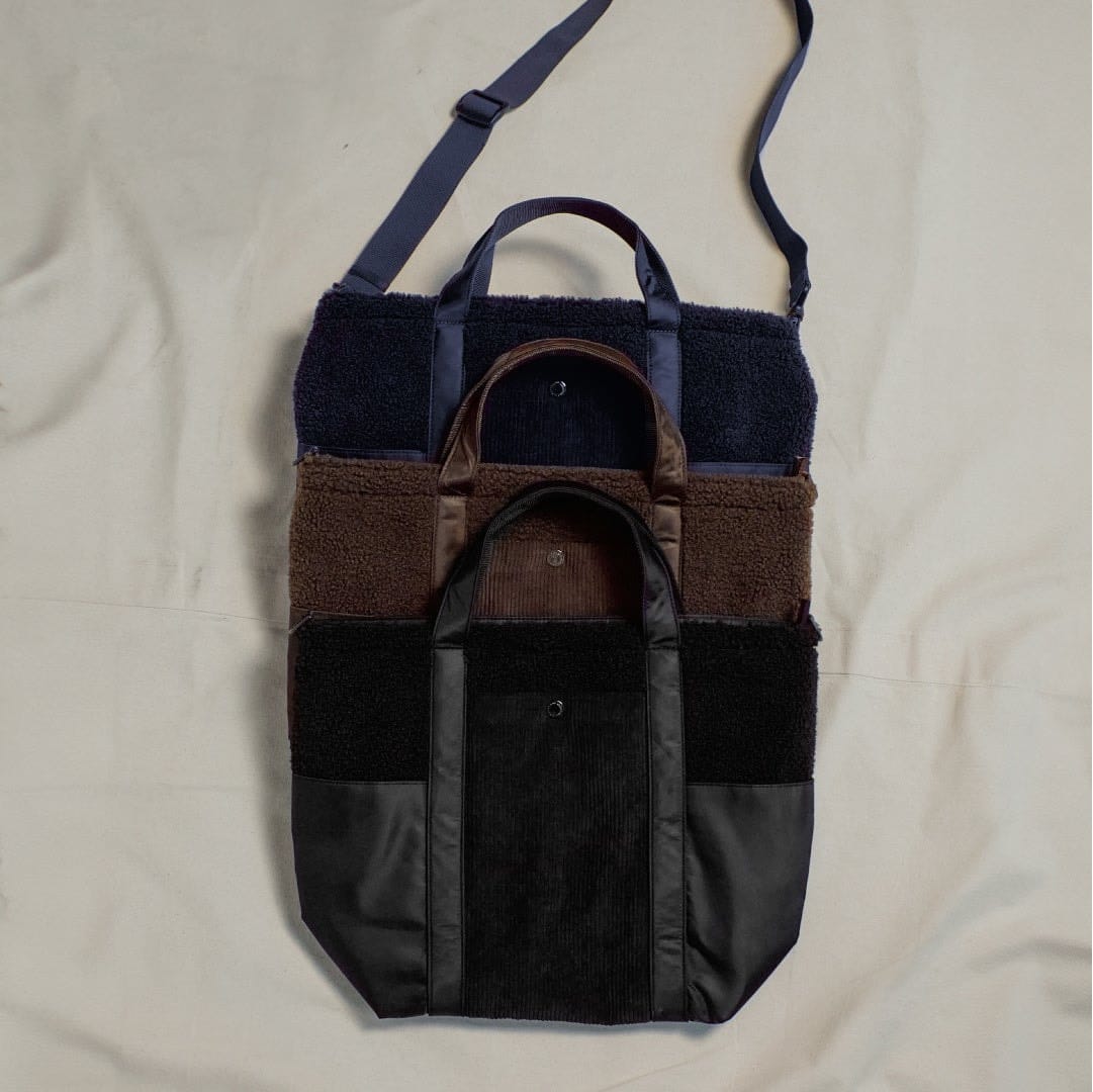Navy, brown and black GU and Engineered Garments tote bags with shoulder straps.