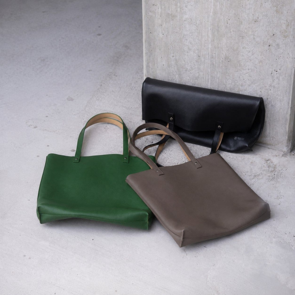 Green, grey and black Kawanishi Dual Every totes arranged on concrete.