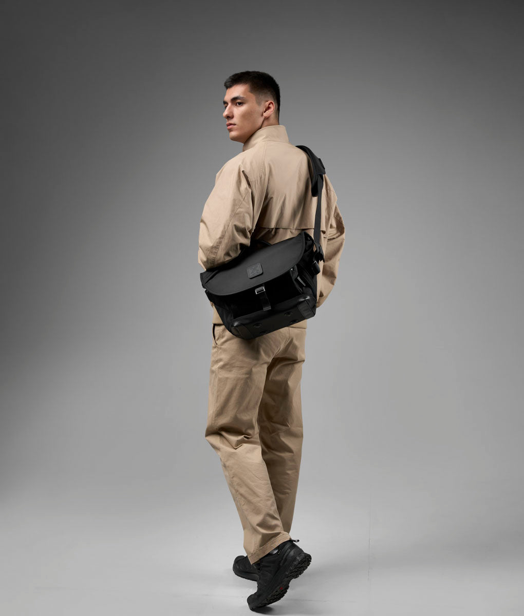 The black ALPAKA 7ven Messenger 14-inch Decade Edition worn across the body.