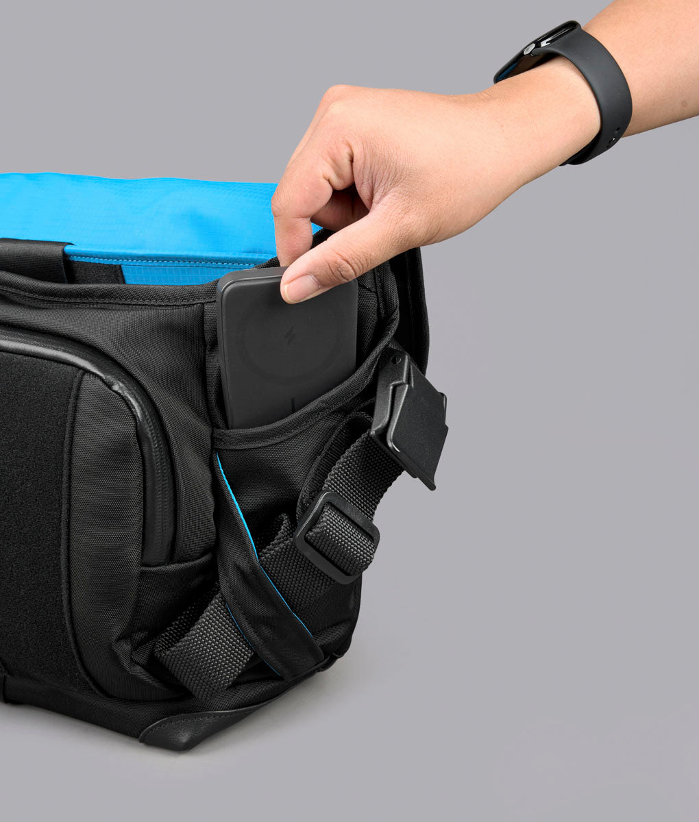 A hand opens a side pocket on the black 7ven Messenger.