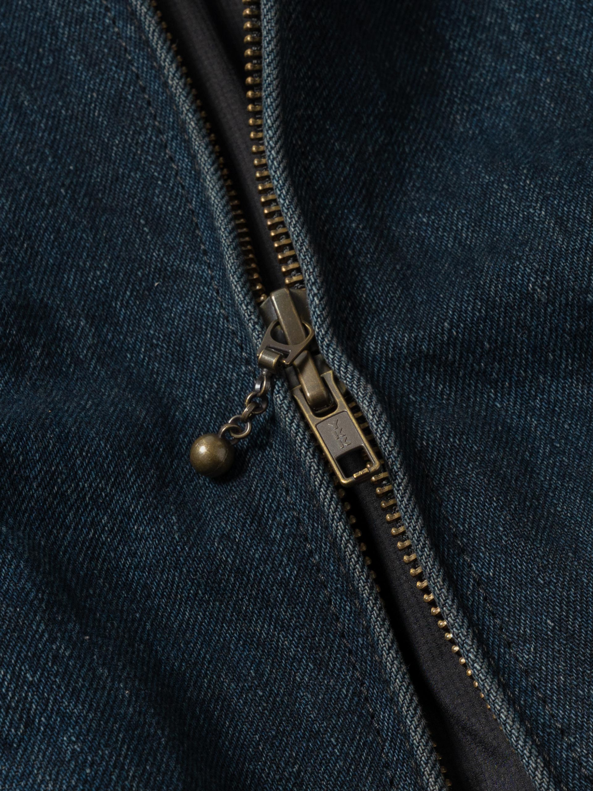Close detail of the blouson's two-way front zip and dark denim texture.