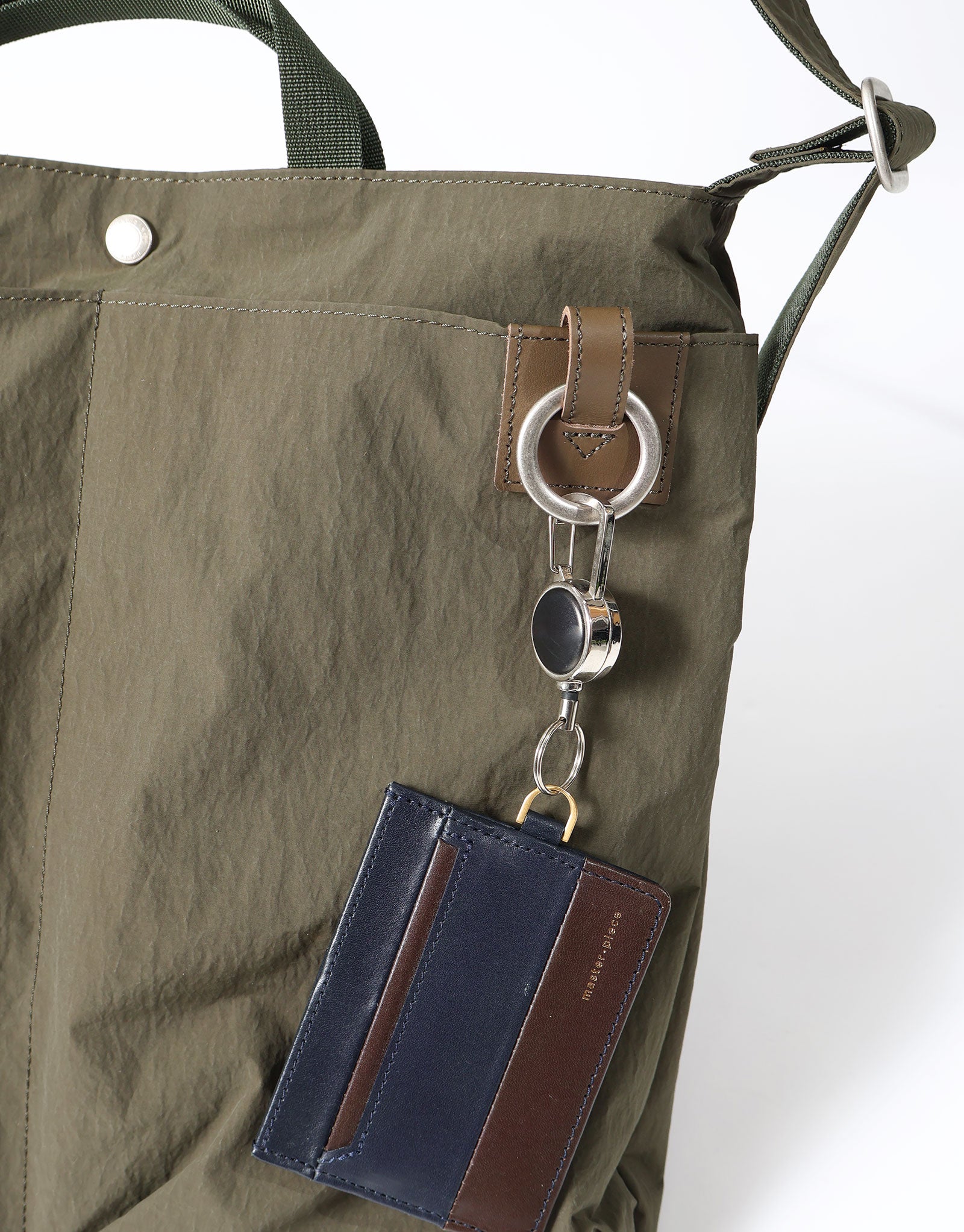 An accessory ring on the Khaki Sash M shown holding a small card case.