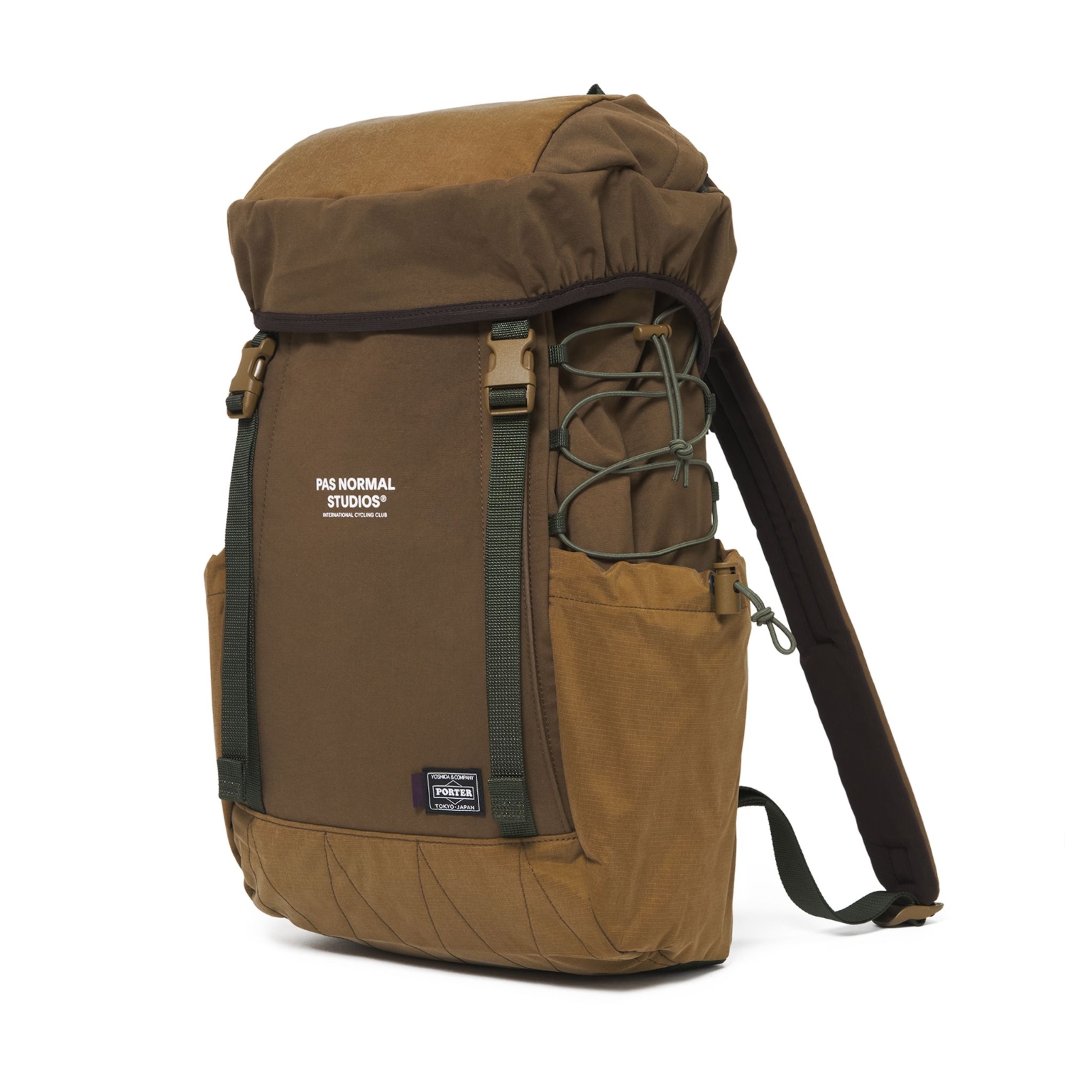 Three-quarter view of the brown Pas Normal Studios × PORTER backpack, with olive webbing and a drawcord side pocket.