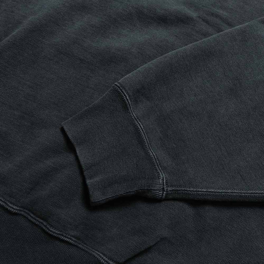Detail of the black REMI RELIEF sweatshirt sleeve, ribbed cuff and seam.