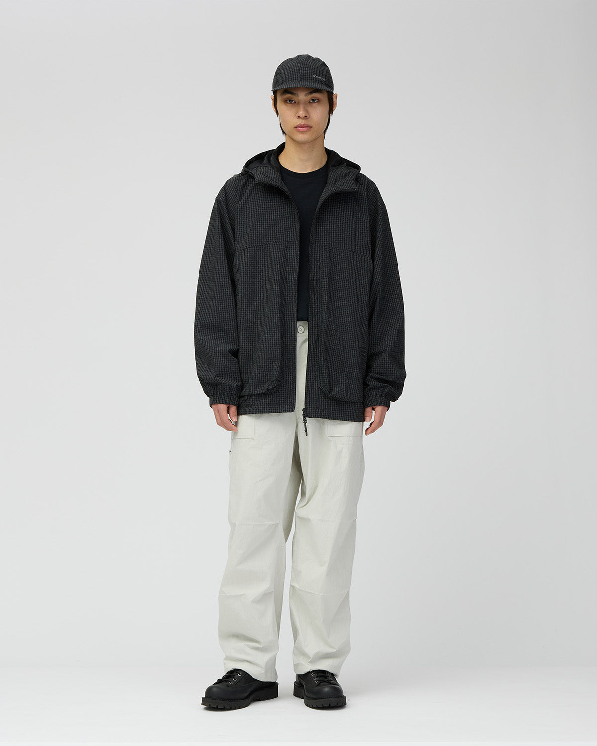 A model wears the black Kasuri Ripstop Jacket with pale trousers.