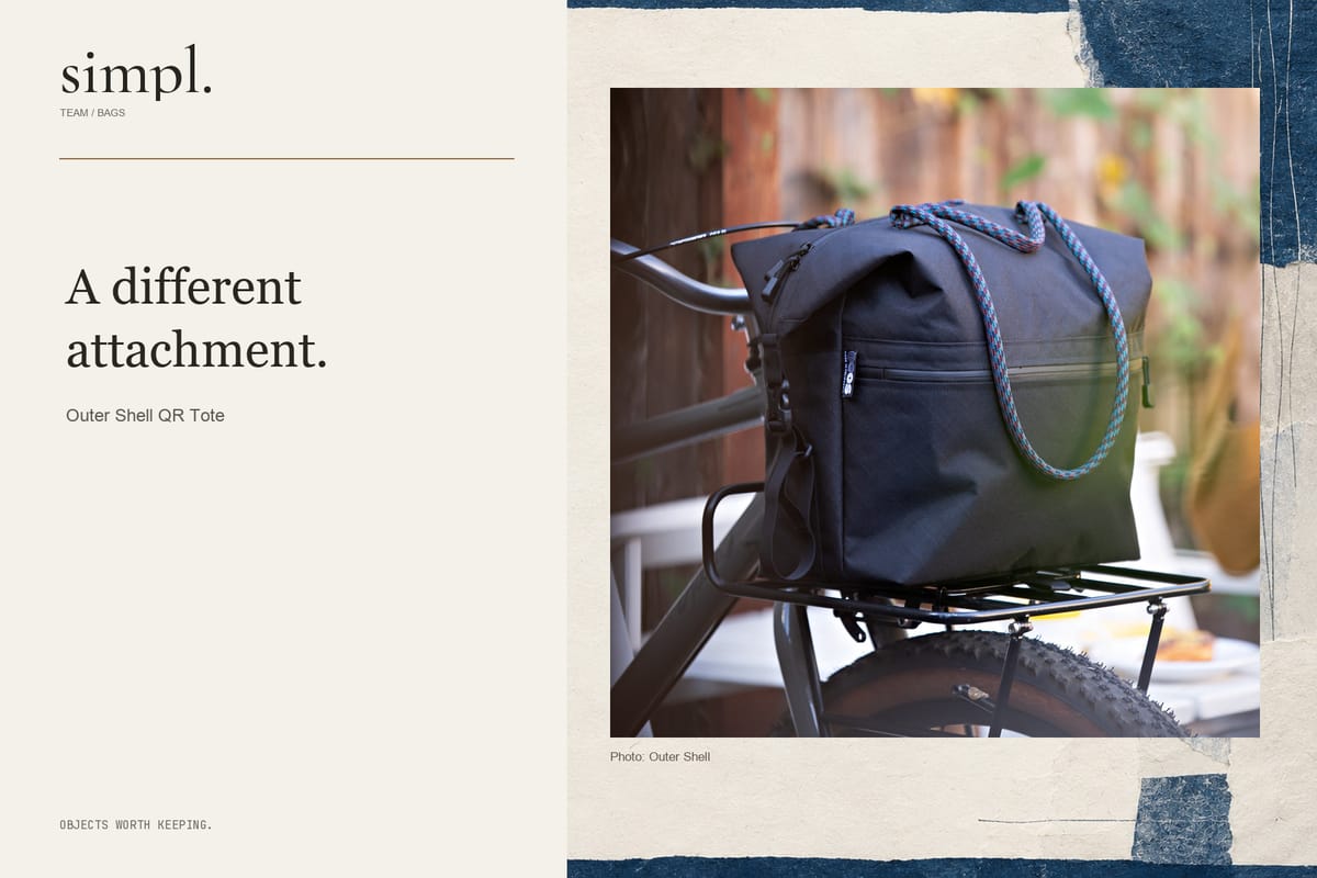 Outer Shell QR Tote with blue and purple handles mounted on a bicycle front rack.